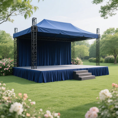 Outdoor event stage with blue canopy and steps, surrounded by greenery and flowers.