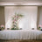 Elegant wedding stage setup with draped white fabric and floral arrangements.