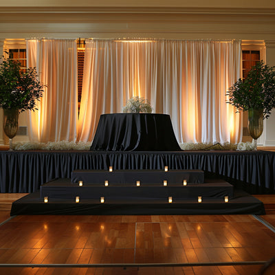 Elegant event stage with draped curtains and candlelit ambiance.