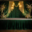 Elegant green stage backdrop with floral arrangements and soft lighting.