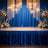 Elegant blue stage backdrop with floral arrangements and hanging lights.