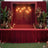 Elegant event stage with red drapery, flowers, and ambient lighting.
