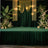 Elegant green event stage with draped fabric and floral arrangements.