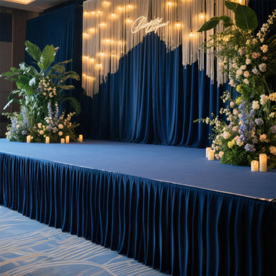Event stage decorated with blue drapes, flowers, and ambient lighting.