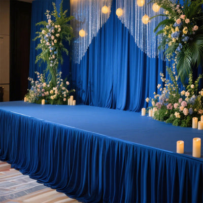 Blue stage setup with floral arrangements and candles for an event.