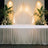 Elegant event stage with draped fabric, greenery, and soft lighting.