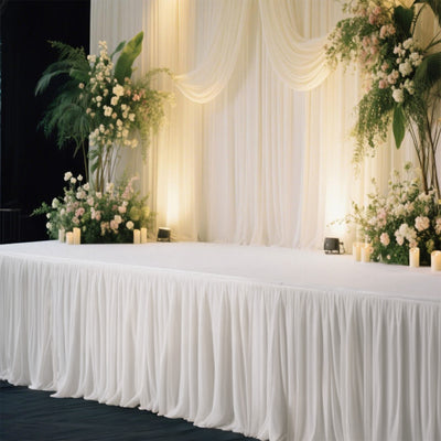 Elegant wedding stage setup with white drapes and floral arrangements.