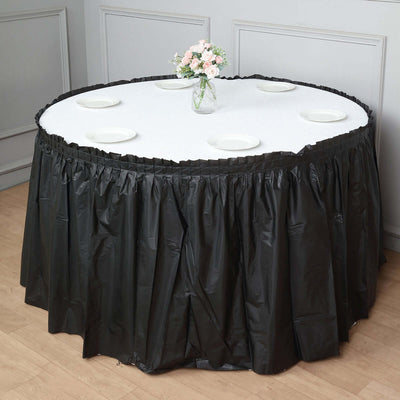 Black table skirt draped around an oval table with a floral centerpiece.