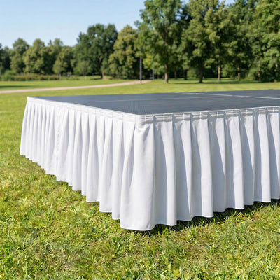 Outdoor table with white pleated skirt on a grassy lawn at a park