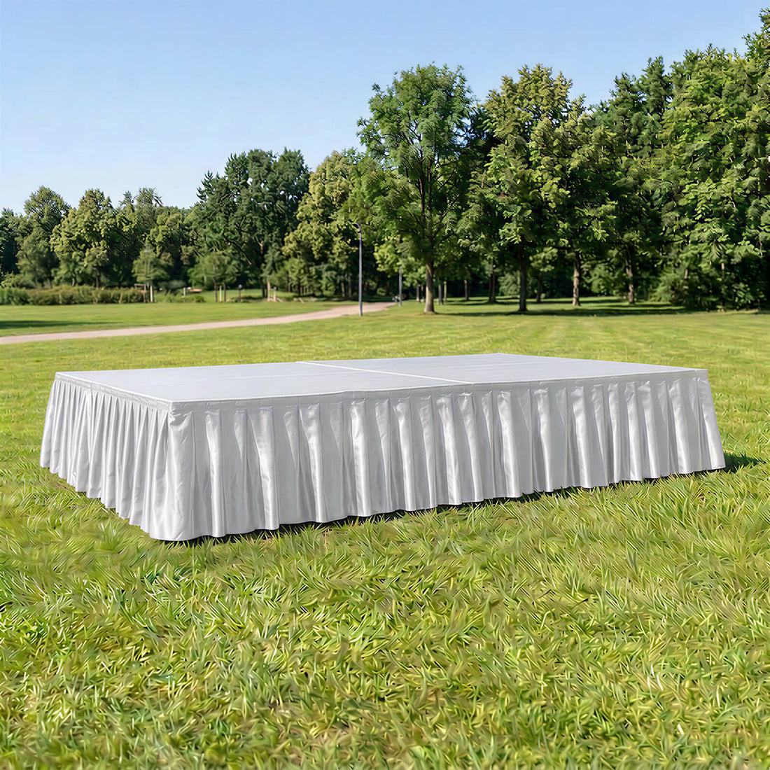 White rectangular outdoor event stage with pleated skirting in a park