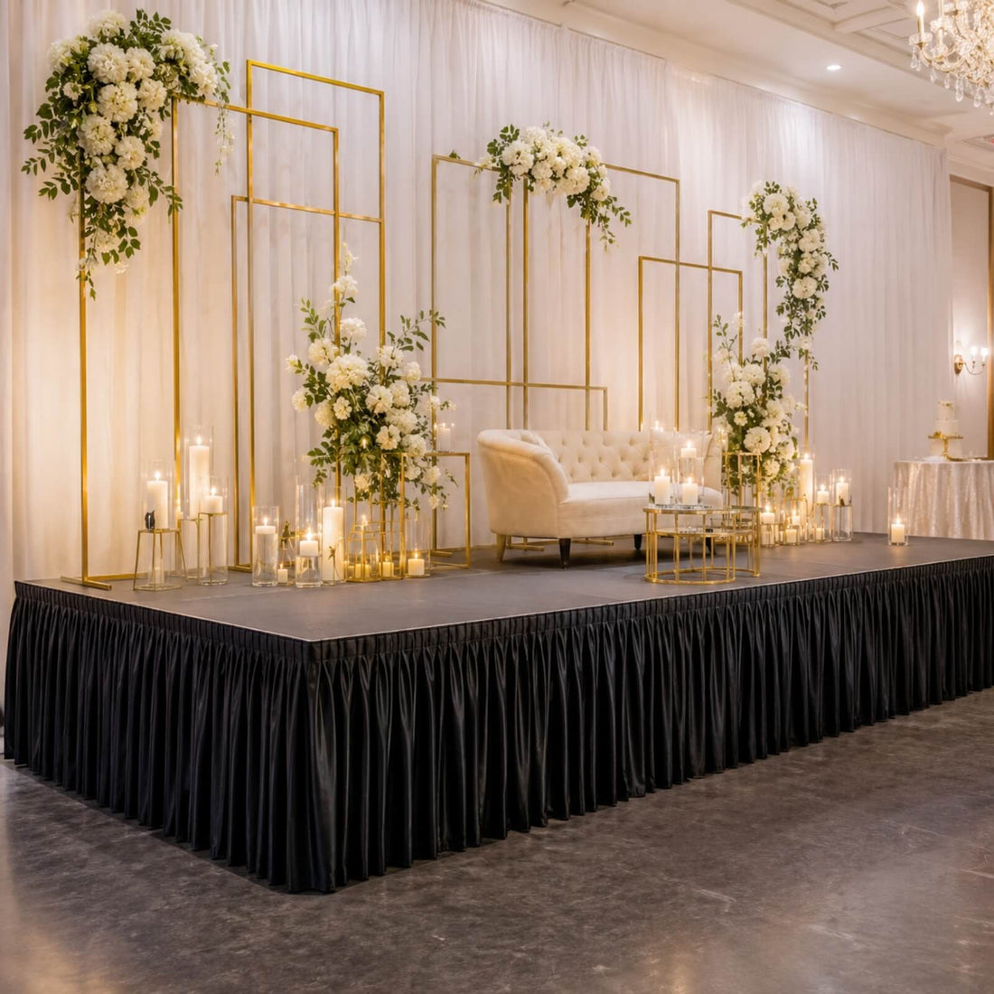 Elegant wedding stage decor with white flowers, gold frames, candles, and loveseat