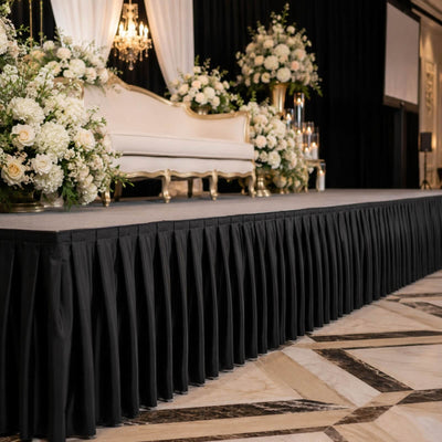 Elegant wedding stage with floral arrangements, draped backdrop, and white loveseat
