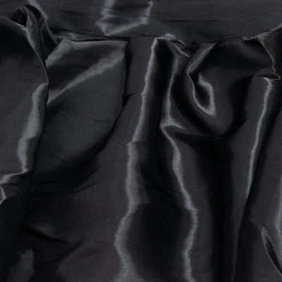 Black shiny satin fabric texture with soft folds and wrinkles