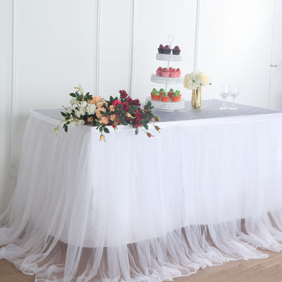 Elegant dessert table with cake stand and floral arrangements in a styled setting.