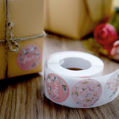 Roll of floral-themed stickers next to wrapped gift boxes.