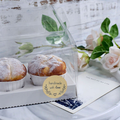 Two freshly baked pastries in a clear box, labeled "handmade with love."
