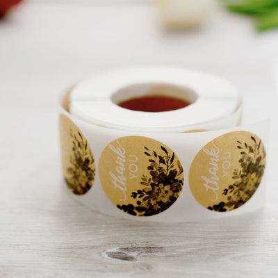 Thank you sticker roll with floral design on a wooden surface.