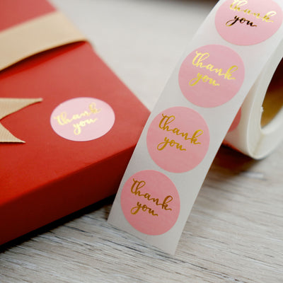 Thank you sticker roll on a gift box with a ribbon.