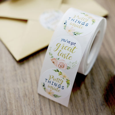 Roll of decorative stickers with floral designs and text, ideal for gift wrapping.