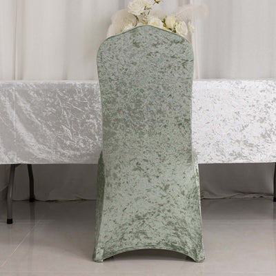 Green velvet chair cover on a table with floral arrangement in the background.