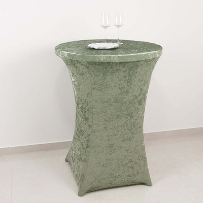 Green velvet table with two wine glasses on top.