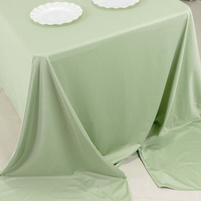 Green tablecloth draped elegantly with white plates on a minimalistic table.