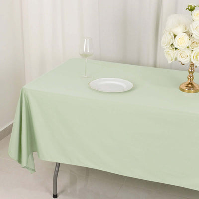 Mint green tablecloth on a dining table with a glass and plate.