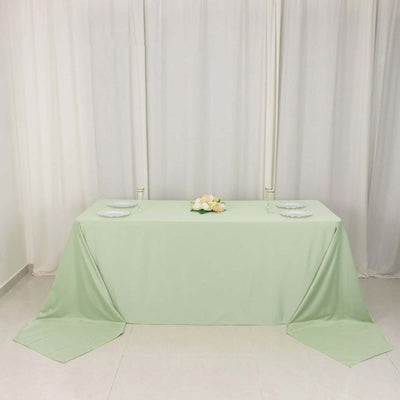 Elegant mint green tablecloth draped over a table with white plates and floral centerpiece.