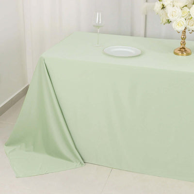 Light green tablecloth draped elegantly over a table with a glass and plate.