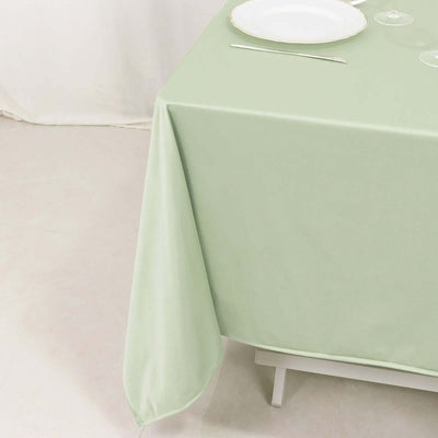 Green tablecloth draped over a table with a plate and glassware.
