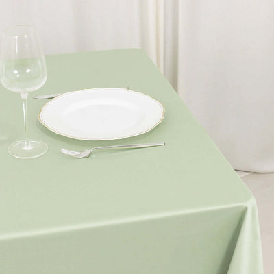 Elegant green tablecloth with fine dining setup, plate, glass, and cutlery.