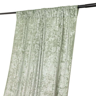 Green velvet curtain draped on a black curtain rod.