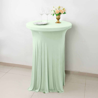 Mint green table cover draped over a round table with decor.