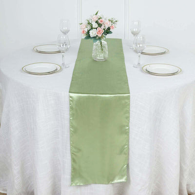 Green satin table runner on a dining table with floral centerpiece and glassware.