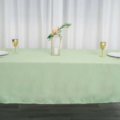 Mint green tablecloth with elegant table setting and floral centerpiece.