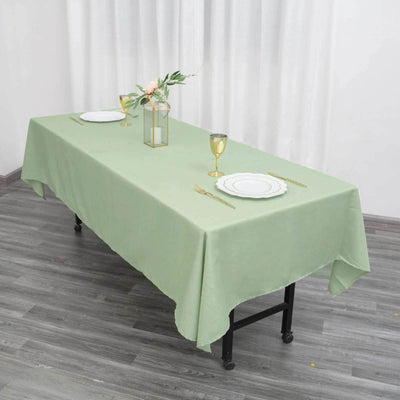 Elegant green tablecloth set for dining with gold accents and floral centerpiece.