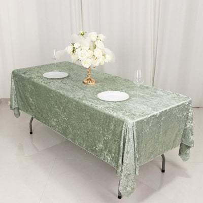 Elegant green tablecloth on a dining table with floral centerpiece and plates.
