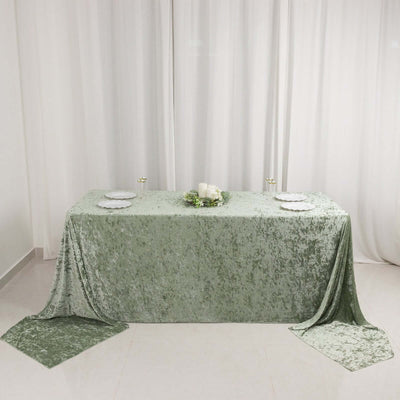 Green velvet tablecloth draped elegantly on a table with plates and candles.