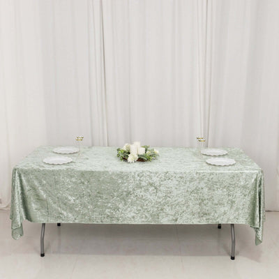 Elegant green velvet tablecloth set for dining with floral centerpiece.