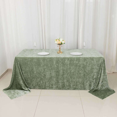 Green velvet tablecloth draped over a table with plates and a floral centerpiece.