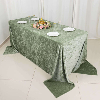 Green velvet tablecloth draped over table with floral centerpiece and plates.