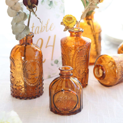 Amber glass vases with dried flowers on a table setting.