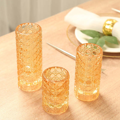 Set of three elegant orange glass candle holders on a dining table.