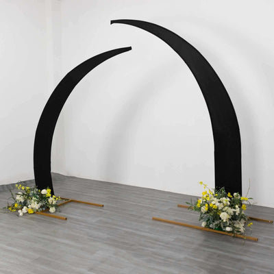 Black arch with floral arrangements on wooden bases in a studio setting.