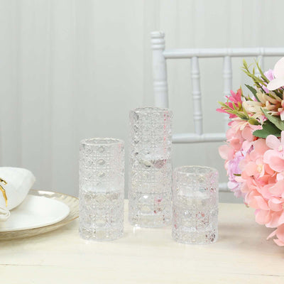 Decorative glass vases in various heights on a table with flowers.