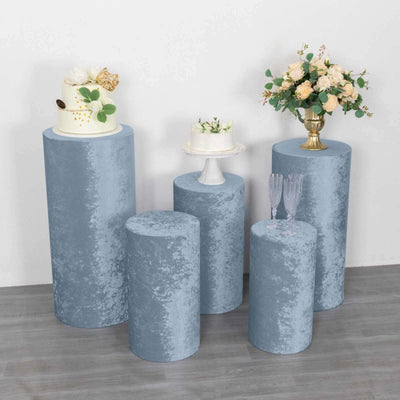 Set of five blue velvet display pedestals with cakes and flowers.