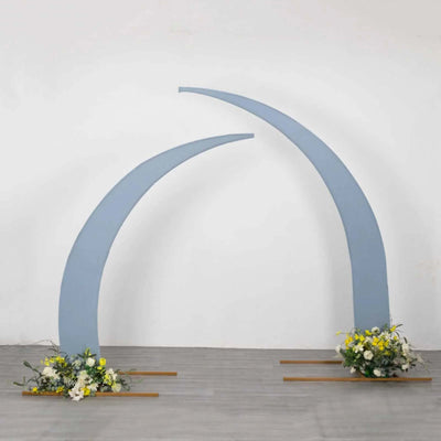 Blue arch structure with floral arrangements at the base on a plain backdrop.