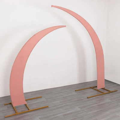 Pink fabric arches on gold stands in a minimalist setting.