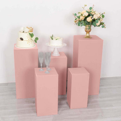 Pink display pedestals with cake and floral arrangements for events and celebrations.