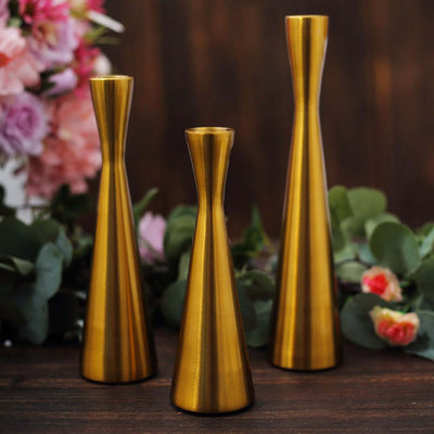 Set of three elegant gold vases in various heights against a floral backdrop.